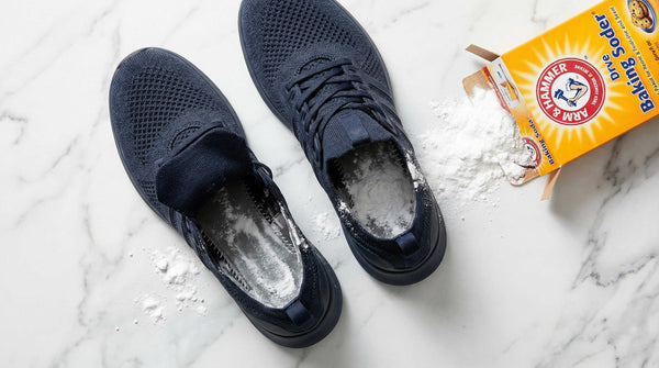 Baking soda spilling out of shoes with white powder residue on dark insoles
