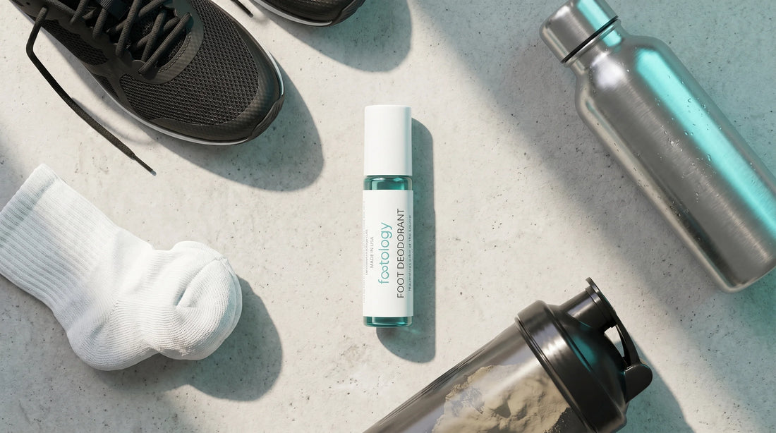 Foot deodorant roll-on next to a water bottle, protein shaker, sock, and running shoe on a counter, post-workout flat lay.